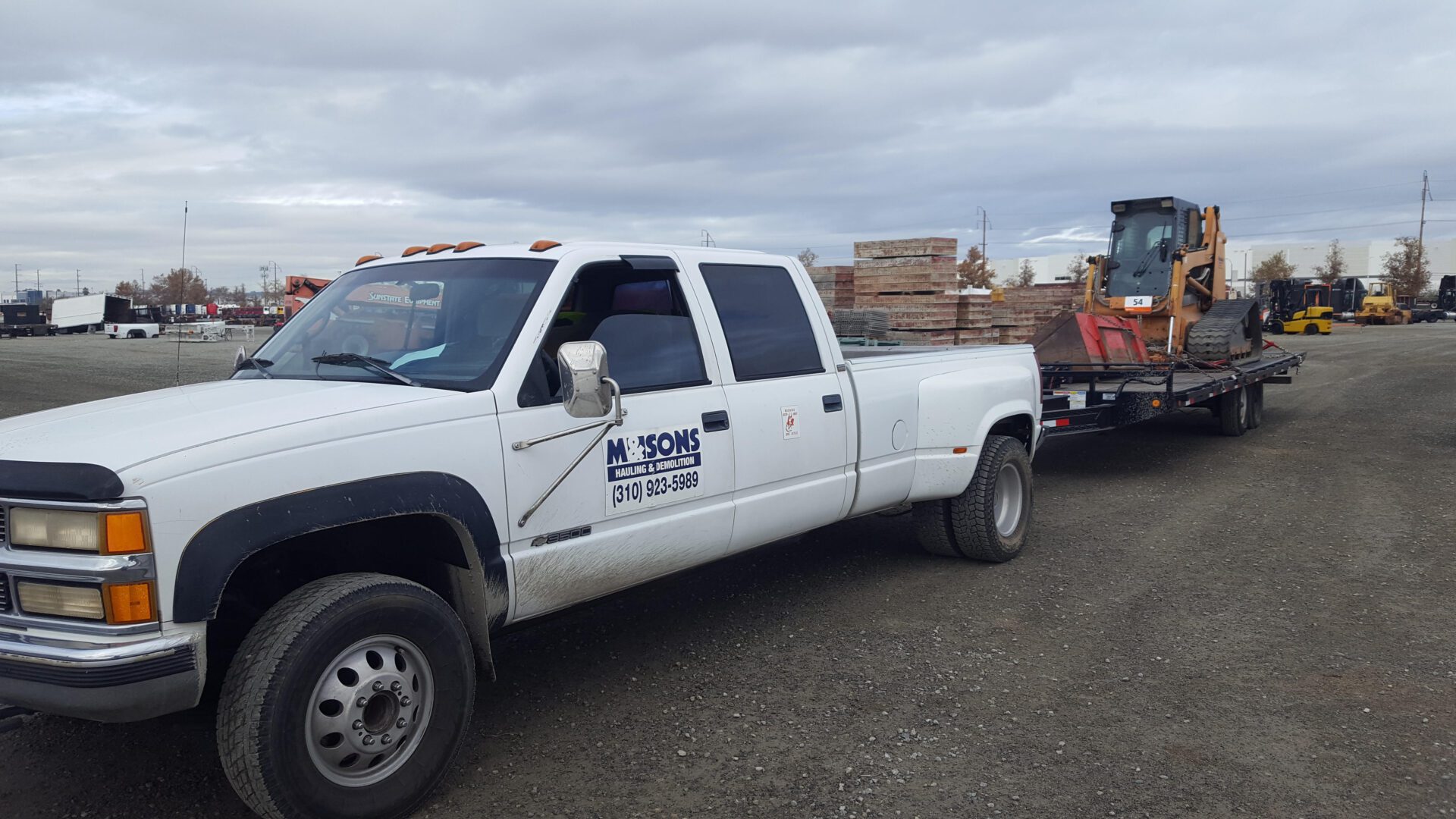 M & sons white truck hauling tractor